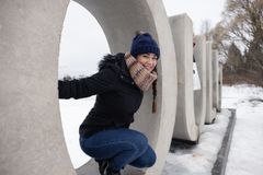 Nuori nainen hymyilee ja istuu suuren betonisen renkaan sisällä lumisessa ulkoilmassa. Betonikirjaimista muodostuu sana Oulu.