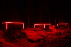 Valotaideteos "Rajapinta" pimeässä metsässä, punaiset valot korostavat maisemaa. Tekijät Meeri Alatalo, Päivi Paakinaho ja Kimmo Hanhela.