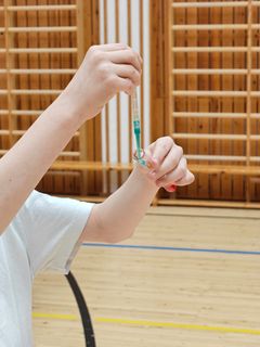 Lapsi pitää käsissään pipettiä laboratoriotilassa.