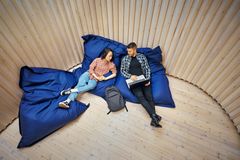 Kaksi henkilöä istuu mukavilla säkkituoleilla puulattialla, keskustellen ja katsoen toisiaan.