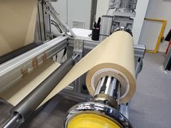 Laite, joka käärii biopohjaista pinnoitemateriaalia rullalle teollisuusympäristössä.