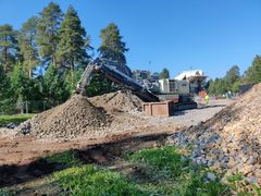 Kone murskaa soraa ulkona aurinkoisena päivänä.