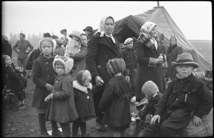 Suomalaisia evakkoja, naisia ja lapsia, ruotsalaissotilaiden vastaanottamina leirin teltan edessä vuonna 1944.