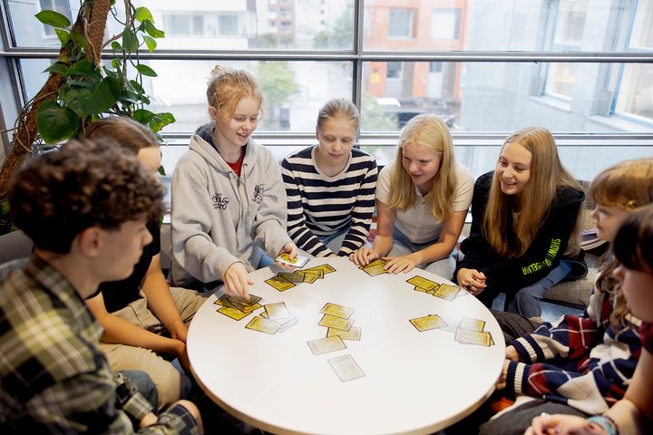 Oppilaita pyöreän pöydän ympärillä tarkastelemassa sanakortteja