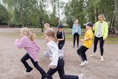 Lapset leikkivät ulkona ohjaajan kanssa.