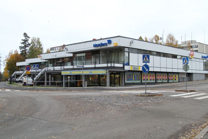 Kulosaaren ostoskeskus on 1960-luvun alusta. Rakennuksessa on valkoista julkisivua, kaksi kerrosta ja mustia yksityiskohtia.