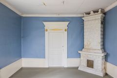 A room with light-blue walls and a white tiled stove.
