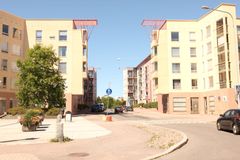 Tyhjä aukio vaaleankeltaisten kerrostalojen edessä.
