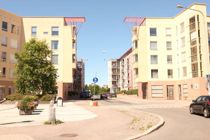 Tyhjä aukio vaaleankeltaisten kerrostalojen edessä.