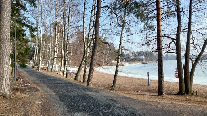 Keväinen uimaranta kuvattuna puistoraitilta päin.