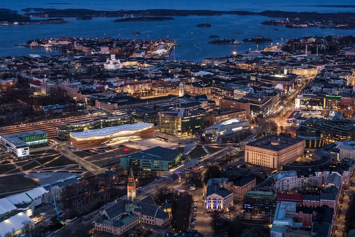 Helsingin keskustaa iltavalaistuksessa, keskellä kuvaa keskustakirjasto Oodi.