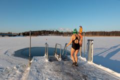Henkilö pipo päässään ja uimapuku päällään astelemassa laiturilla kohti avantoa.