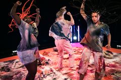 Kolme nuorta tanssijaa The Lava Forest -esityksen värikkäässä ympäristössä.