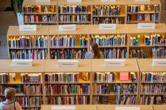 En kvinna står framför hyllor fyllda med böcker i ett bibliotek.