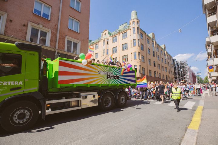 Värikkäitä lippuja, kylttejä, ilmapalloja ja kymmeniä nuoria osallistumassa Helsinki Pride -kulkueeseen Helsingin keskustassa