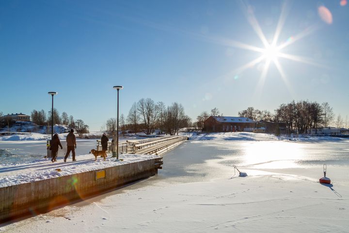 Ulkoilijoita Uunisaaren sillalla talvisessa auringonpaisteessa.