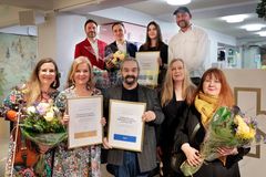 En grupp prisbelönta personer ler mot kameran medan de håller blommor och diplom i händerna.