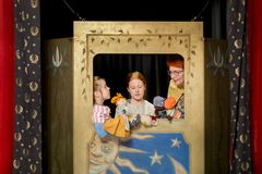 Två barn och en vuxen leker med handdockor i Barnens stad på Helsingfors stadsmuseum.