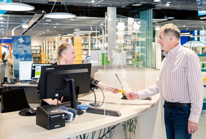 Person vid informationsdisk i biblioteket.