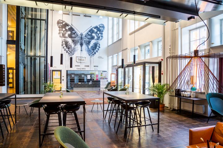 Bild av en modern och välkomnande interiör på ett kulturcentrum med högt i tak och ett stort fjärilsmönster på väggen.