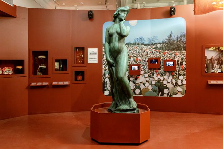 Näkymä Helsingin kaupunginmuseon uudesta näyttelystä. Keskellä Havis Amandan näköispatsas, taustalla valokuvia ja museoesineitä.