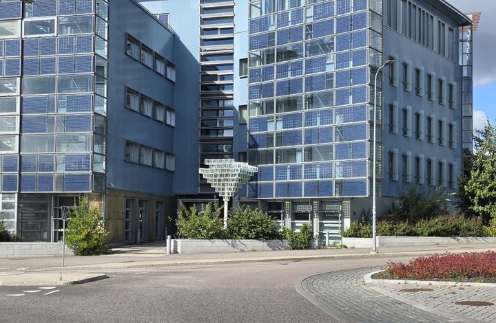 Bild av en modern byggnad med glasfasad och flera våningar.