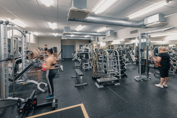Alt-teksti: Ihmiset kuntoilevat kuntosalilla, jossa on erilaisia kuntolaitteita.