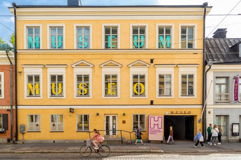 Jalankulkijoita ja pyöräilijä Helsingin kaupunginmuseon edustalla.