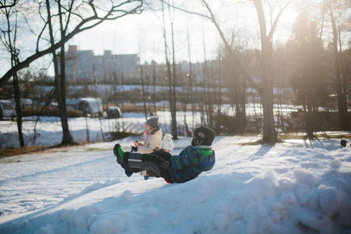 Kaksi lasta ja yksi aikuinen liikkuvat talvisessa kaupunkiluonnossa.