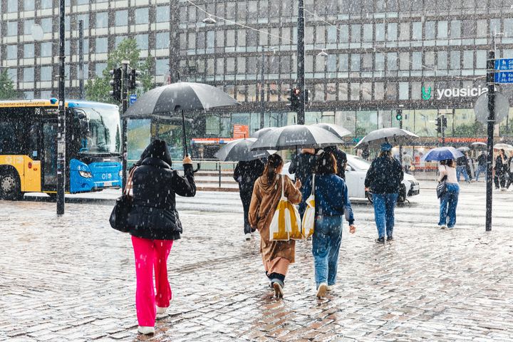 Ihmisiä vesisateessa Helsingin keskustassa.