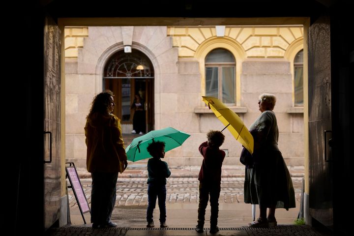 Ihmisiä sateenvarjoineen siirtymässä sateiselle kadulle.