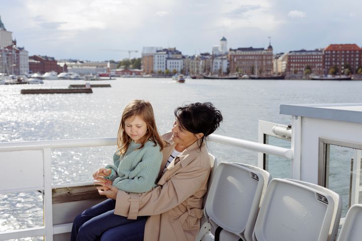 Nainen ja lapsi risteilyaluksen kannella, taustalla Helsingin keskustan rantaviivaa.