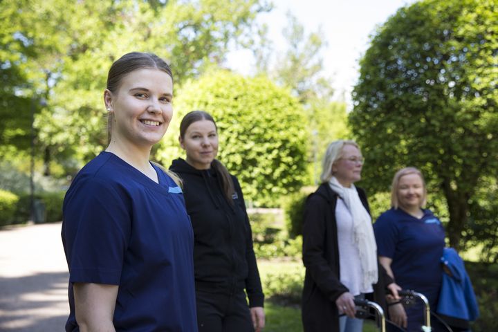 Kuvassa hoitohenkilökuntaa ja asiakkaita ulkoilemassa.