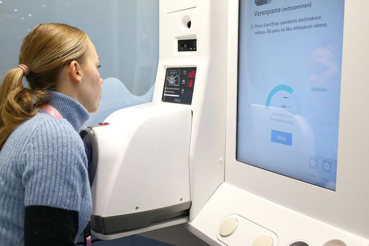 Nainen mittaa verenpaineensa itsemittauspisteellä.