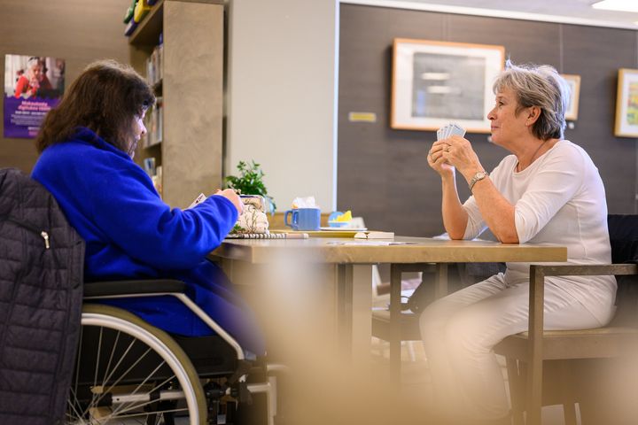 Två personer sitter vid ett bord och spelar kort tillsammans.
