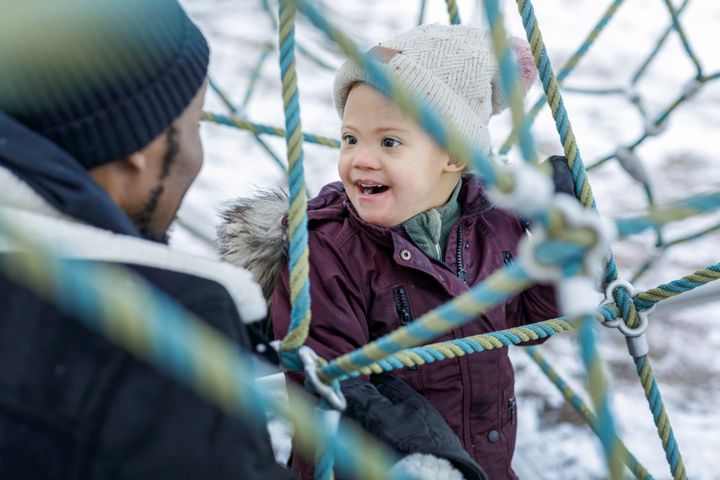Mies ja lapsi hymyilevät toisilleen leikkipuiston kiipeilytelineessä.