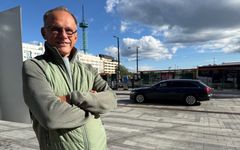 Mies kadulla katsoo kameraan, taustalla liikenteessä auto.