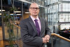 Asiantuntija katsoo kameraan puku päällä modernissa toimistorakennuksessa.