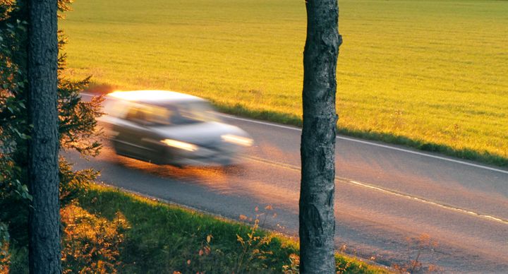 Auto ajaa tiellä aurinkoisella säällä.