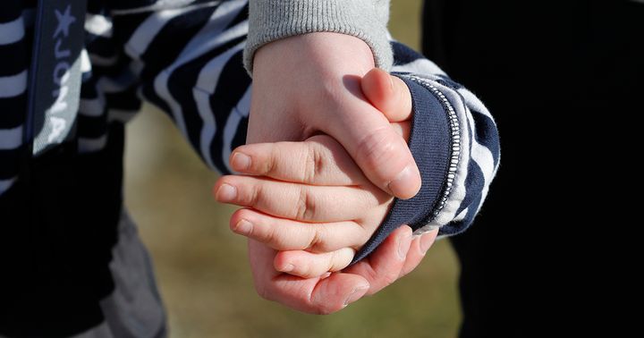 Aikuinen ja lapsi pitävät toisiaan kädestä lähikuvassa.