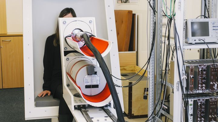 A person sits in a radioactivity measuring device.