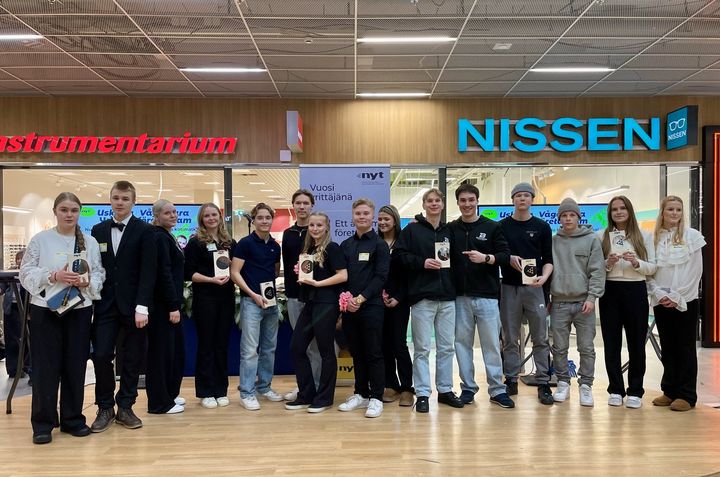 Joukko nuoria poseeraa lavalla kameralle.