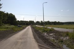 Asfaltin päällystämä pyörätie kulkee maaseudulla kirkkaassa päivänvalossa. Vasemmalla on metsää ja oikealla viljelysmaata.