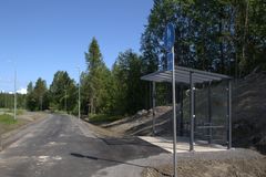 Cykelparkeringstak vid skogskanten, intill en asfalterad väg.