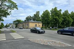 Katunäkymä, jossa autoja ajaa risteyksen läpi ja taustalla on vaalea, vanha rakennus.