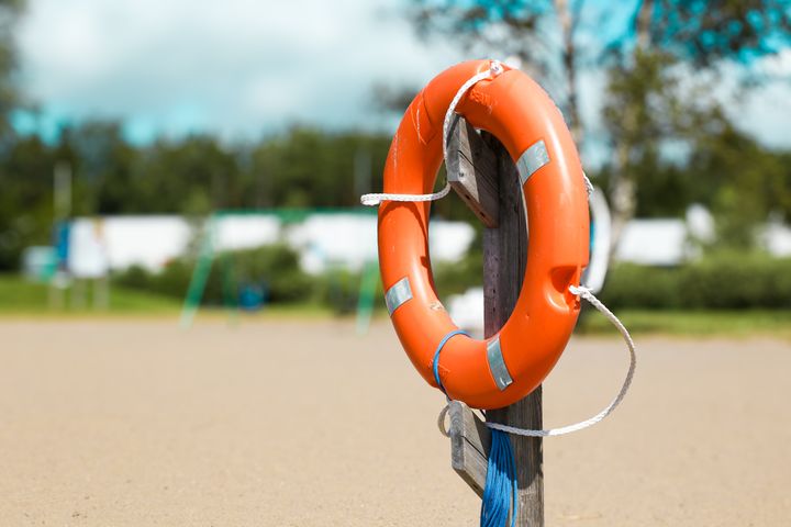 En orange livboj hänger på en stolpe vid en strand.