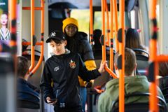 En unge går genom en buss medan andra passagerare sitter.