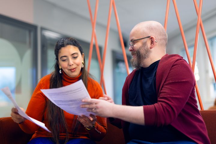 Två personer sitter och diskuterar över ett dokument.