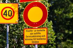 Trafikskyltar mot gröna buskar, inklusive en skylt med text på finska och svenska om tillåten servicekörning.