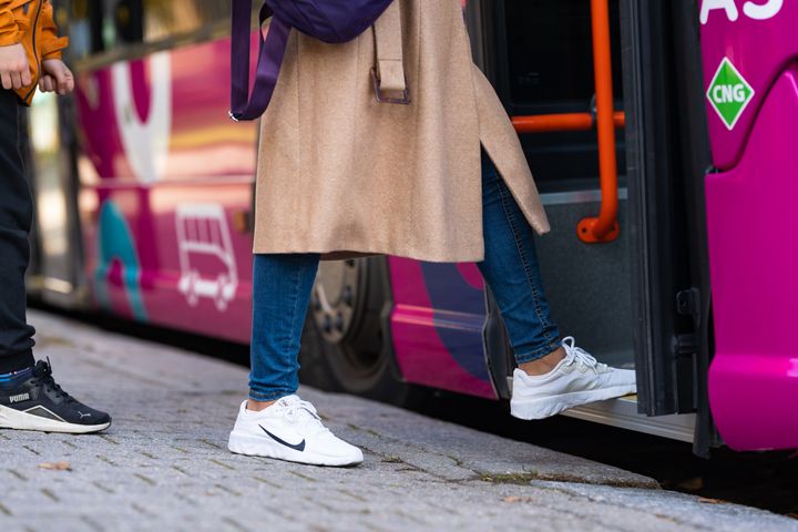Henkilö nousemassa bussiin, näkyvissä jalat ja lenkkarit.